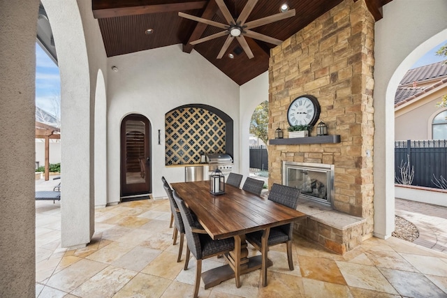 dining space with beam ceiling, an outdoor stone fireplace, high vaulted ceiling, and wood ceiling