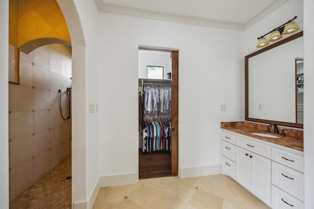 bathroom featuring crown molding, tile patterned floors, vanity, and a tile shower