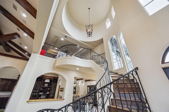 foyer featuring beam ceiling, a notable chandelier, and a towering ceiling