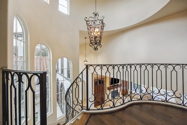 interior space with hardwood / wood-style flooring, a towering ceiling, and a chandelier