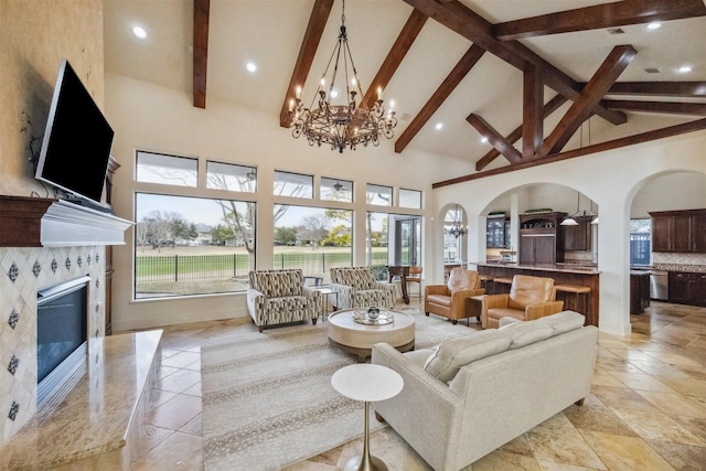 living room featuring beam ceiling, a chandelier, a fireplace, and high vaulted ceiling