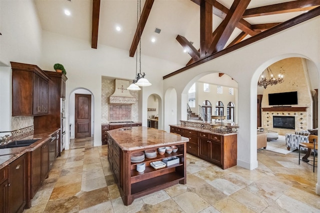 kitchen with sink, backsplash, hanging light fixtures, a center island, and light stone countertops