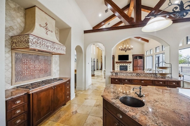 kitchen featuring tasteful backsplash, light stone countertops, sink, and custom range hood