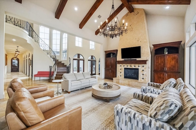 living room featuring beamed ceiling, a tiled fireplace, high vaulted ceiling, and a notable chandelier