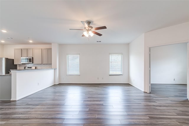 unfurnished living room with dark wood-type flooring and ceiling fan