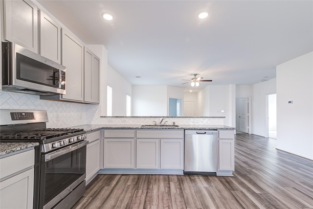 kitchen with white cabinetry, appliances with stainless steel finishes, sink, and light stone counters