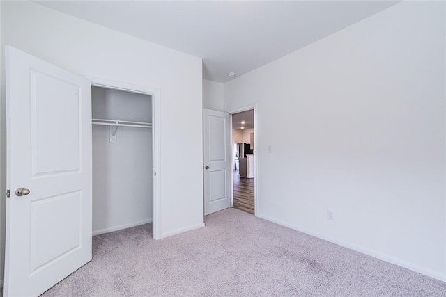 unfurnished bedroom featuring light colored carpet and a closet