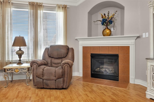 sitting room with ornamental molding, light hardwood / wood-style floors, and a tile fireplace