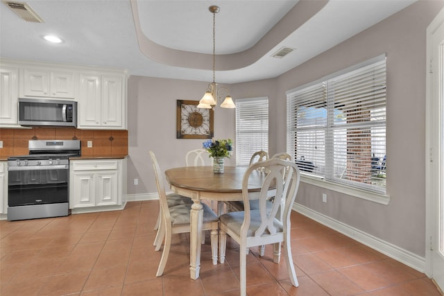 dining room with a raised ceiling and light tile patterned floors