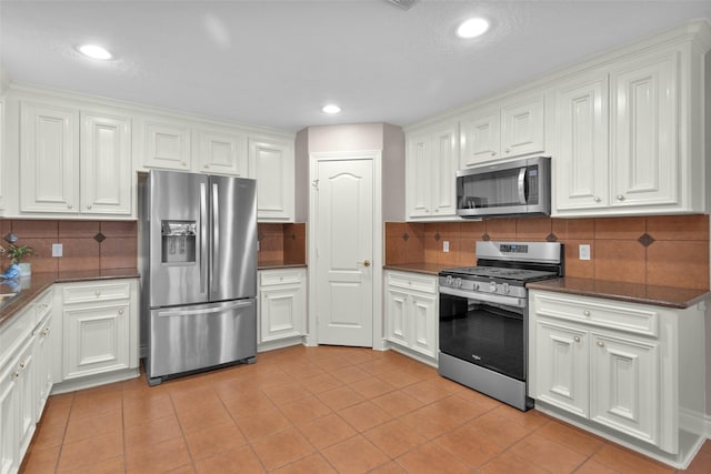 kitchen featuring decorative backsplash, light tile patterned flooring, white cabinets, and appliances with stainless steel finishes