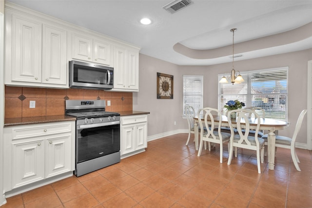 kitchen featuring pendant lighting, white cabinetry, stainless steel appliances, tasteful backsplash, and a tray ceiling