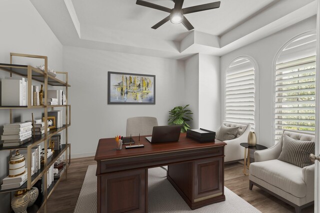 office with a raised ceiling, dark wood-type flooring, and ceiling fan