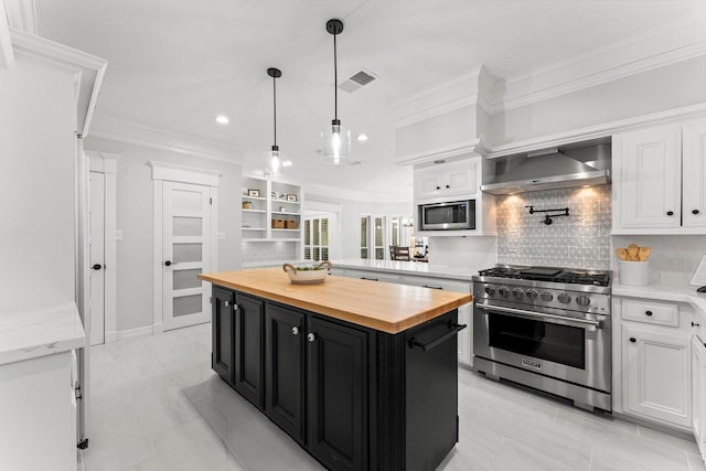 kitchen featuring a kitchen island, appliances with stainless steel finishes, wall chimney range hood, and white cabinets