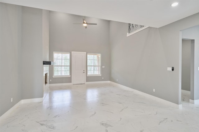 unfurnished living room with ceiling fan and a high ceiling