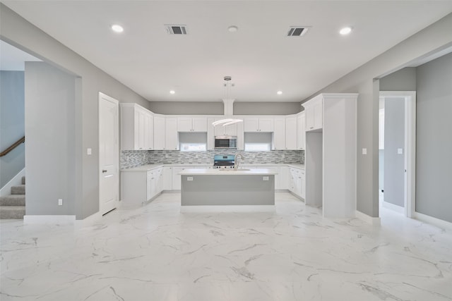 kitchen with pendant lighting, sink, white cabinetry, a kitchen island with sink, and stainless steel appliances