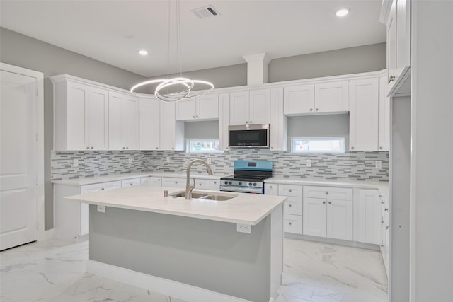 kitchen featuring sink, backsplash, stainless steel appliances, an island with sink, and white cabinets