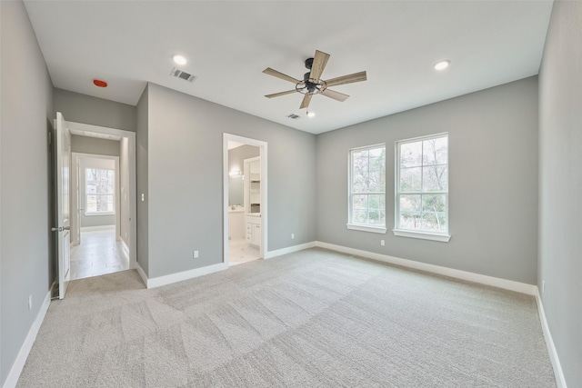 unfurnished bedroom with ceiling fan, light colored carpet, and ensuite bathroom