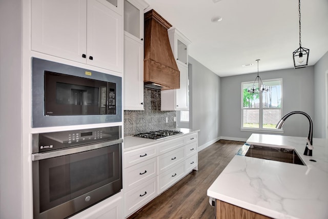 kitchen with white cabinetry, light stone countertops, stainless steel appliances, and custom range hood