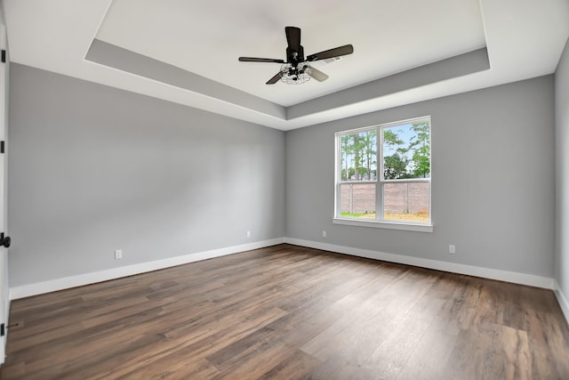 empty room featuring ceiling fan, dark hardwood / wood-style floors, and a raised ceiling