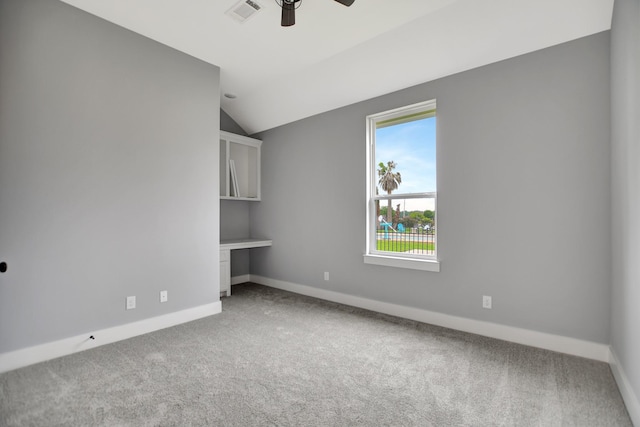 unfurnished bedroom with ceiling fan, carpet flooring, built in desk, and vaulted ceiling