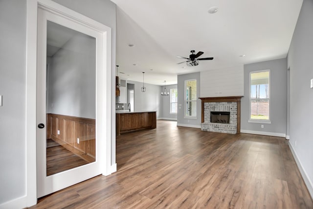 unfurnished living room featuring a brick fireplace, hardwood / wood-style flooring, sink, and ceiling fan