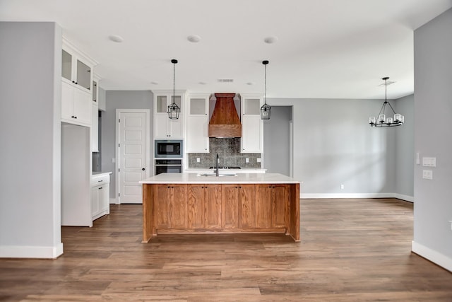 kitchen featuring built in microwave, sink, white cabinetry, custom range hood, and a large island