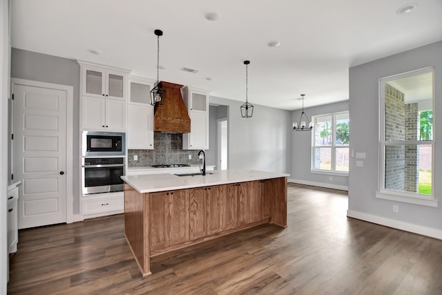 kitchen featuring a spacious island, built in microwave, sink, white cabinetry, and stainless steel oven