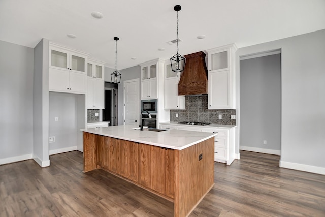 kitchen with sink, gas cooktop, premium range hood, an island with sink, and white cabinets