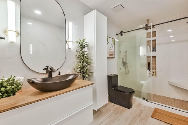 bathroom featuring vanity, toilet, hardwood / wood-style floors, and a shower with shower door