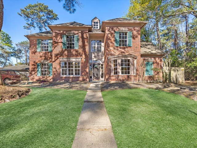 view of front of house featuring a front lawn, fence, and brick siding