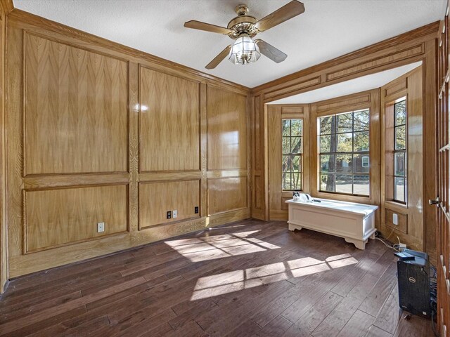 unfurnished room with dark wood-style floors, wooden walls, and ceiling fan