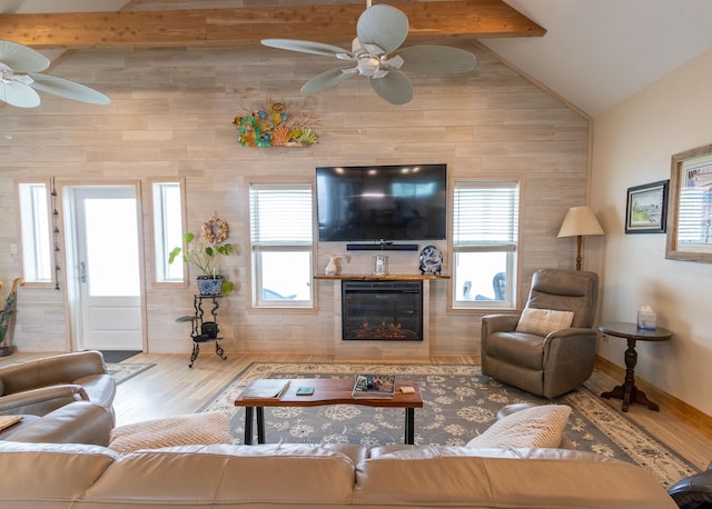 living room with hardwood / wood-style flooring, a wealth of natural light, lofted ceiling with beams, and a large fireplace