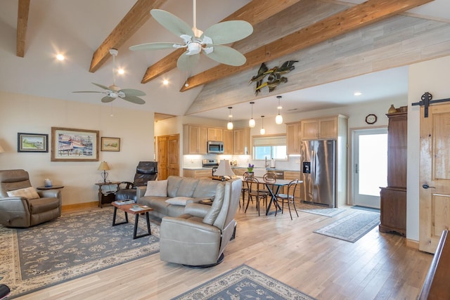 living room with lofted ceiling with beams, sink, ceiling fan, a barn door, and light hardwood / wood-style flooring