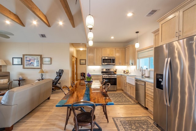 kitchen with light brown cabinetry, hanging light fixtures, light hardwood / wood-style flooring, and appliances with stainless steel finishes