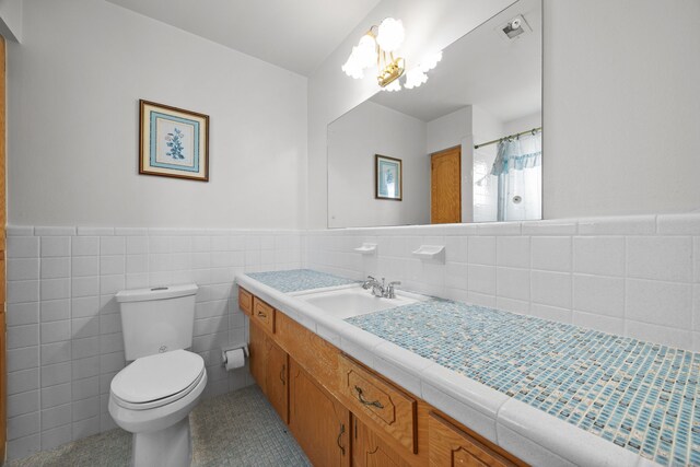 bathroom with tile walls, a chandelier, vanity, toilet, and a shower with shower curtain