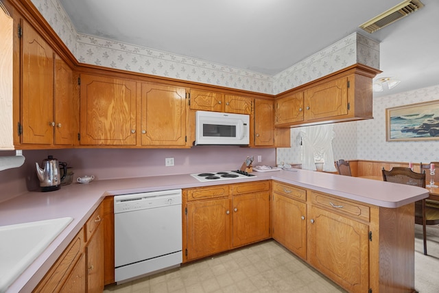 kitchen featuring white appliances, kitchen peninsula, and sink