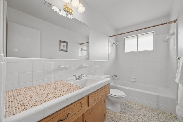 full bathroom featuring toilet, tiled shower / bath, tile walls, vanity, and backsplash