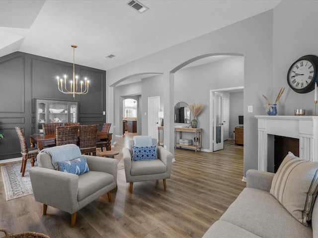 living room featuring vaulted ceiling, dark hardwood / wood-style floors, and an inviting chandelier