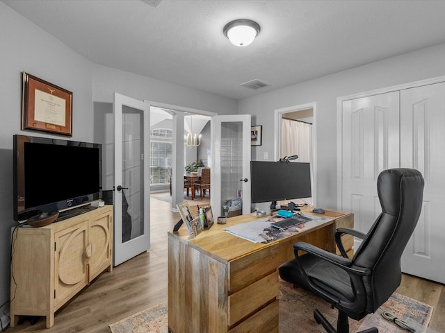 office featuring french doors, an inviting chandelier, and hardwood / wood-style floors