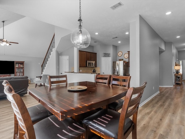 dining area with vaulted ceiling, ceiling fan, and light wood-type flooring