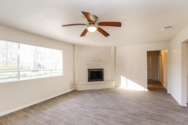 unfurnished living room with ceiling fan and a fireplace