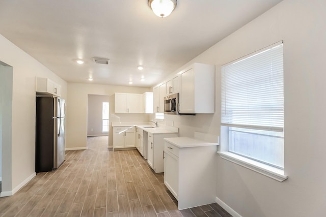 kitchen featuring white cabinetry, appliances with stainless steel finishes, sink, and light hardwood / wood-style flooring