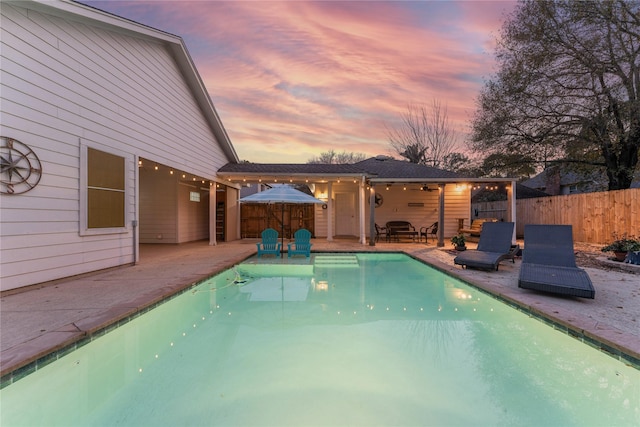 pool at dusk with a patio area