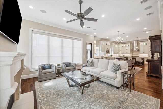 living room with ornamental molding, ceiling fan with notable chandelier, and hardwood / wood-style floors