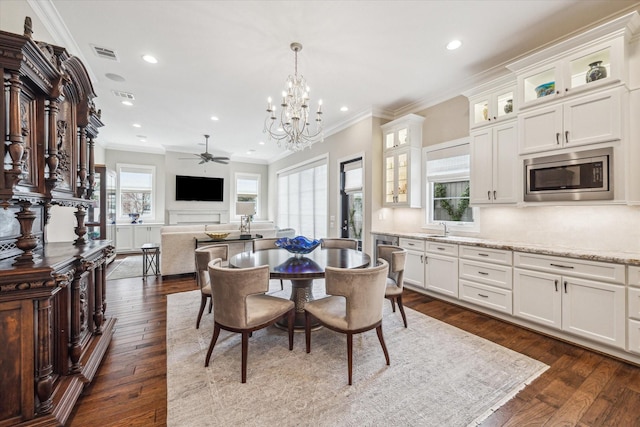 dining room with ornamental molding, dark hardwood / wood-style floors, and ceiling fan with notable chandelier