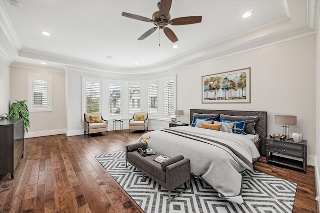 bedroom with dark hardwood / wood-style flooring, a tray ceiling, crown molding, and ceiling fan