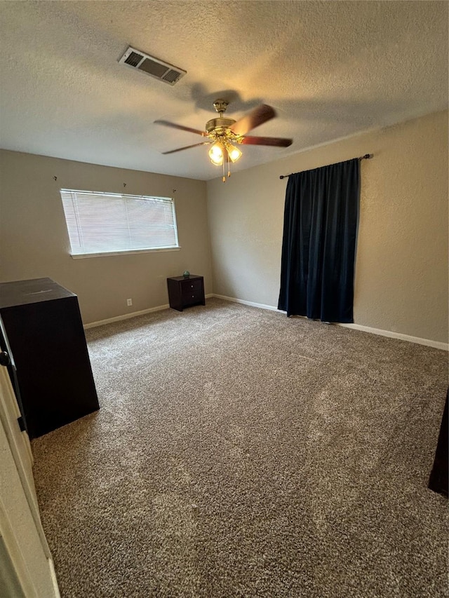 spare room featuring ceiling fan, carpet flooring, and a textured ceiling