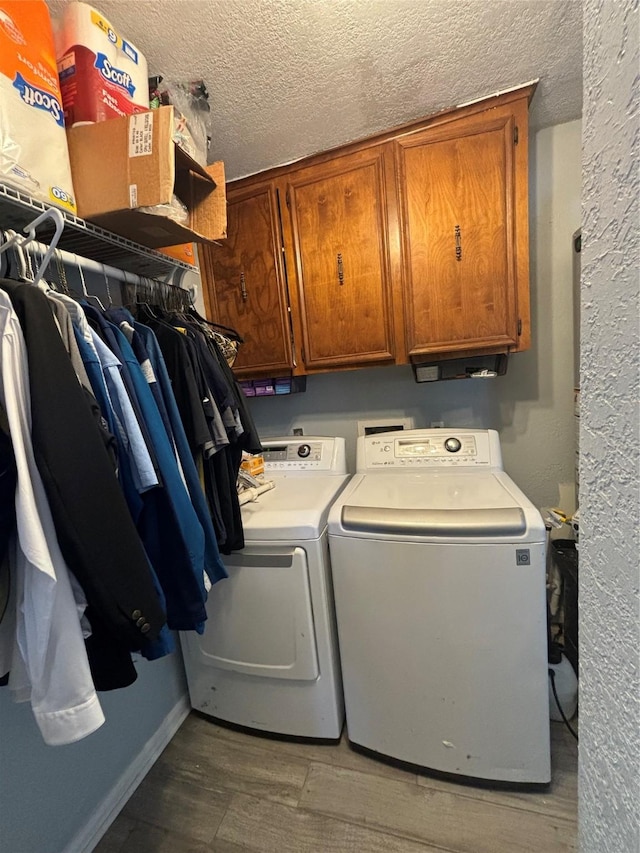 laundry area featuring independent washer and dryer, cabinets, dark hardwood / wood-style flooring, and a textured ceiling