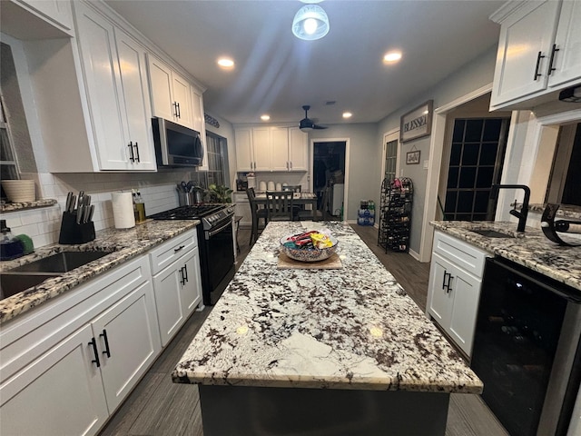 kitchen with a kitchen island, sink, white cabinets, and black appliances