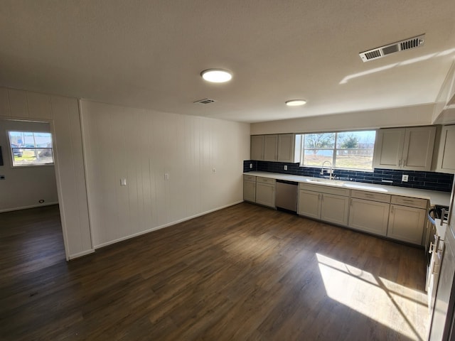 kitchen with dark wood-type flooring, sink, tasteful backsplash, dishwasher, and a healthy amount of sunlight